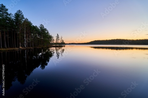 a clear body of water with trees on both sides and the water still reflects a