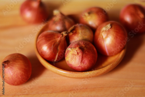 Shallot onions in a wooden bowl on a wooden background.