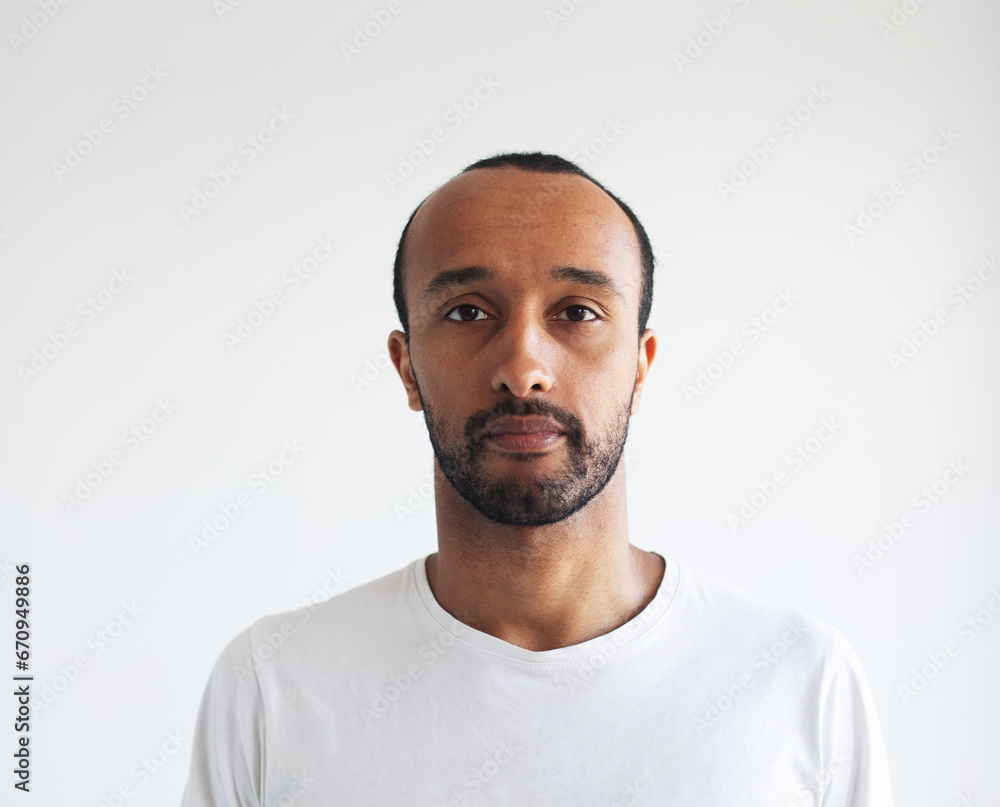 A young unshaven man on a light gray background. A young unshaven man on a light gray background.