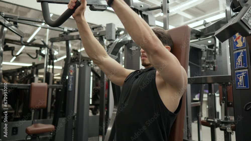 Mascular Man in 40th Doing Machine Chest Press Exercise in Modern Gym Mascular Man in 40th Doing Machine Chest Press Exercise in Modern Gym