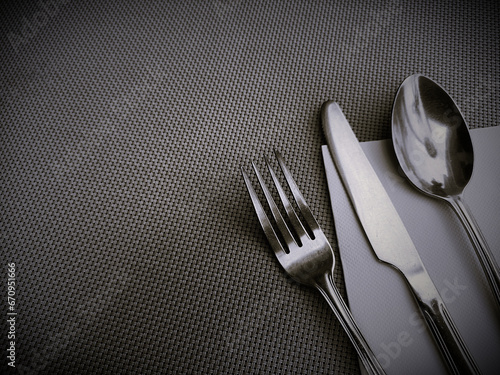 Stainless spoon, fork, knife, and napkin put on a mat. Global Food Crisis concept background, black and white