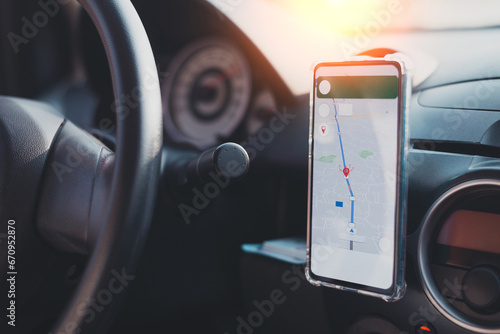 The phone's map appears on the dashboard and street in the background. White cell phone mounted in a mounting with GPS navigation and a map. duplicate the space. photo