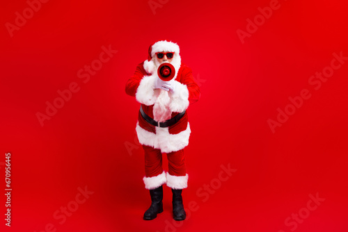 Full body portrait of nice aged santa communicate loudspeaker empty space christmas ad isolated on red color background