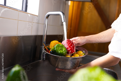 Caucasian male chef washing vegetables in sink in restaurant kitchen photo