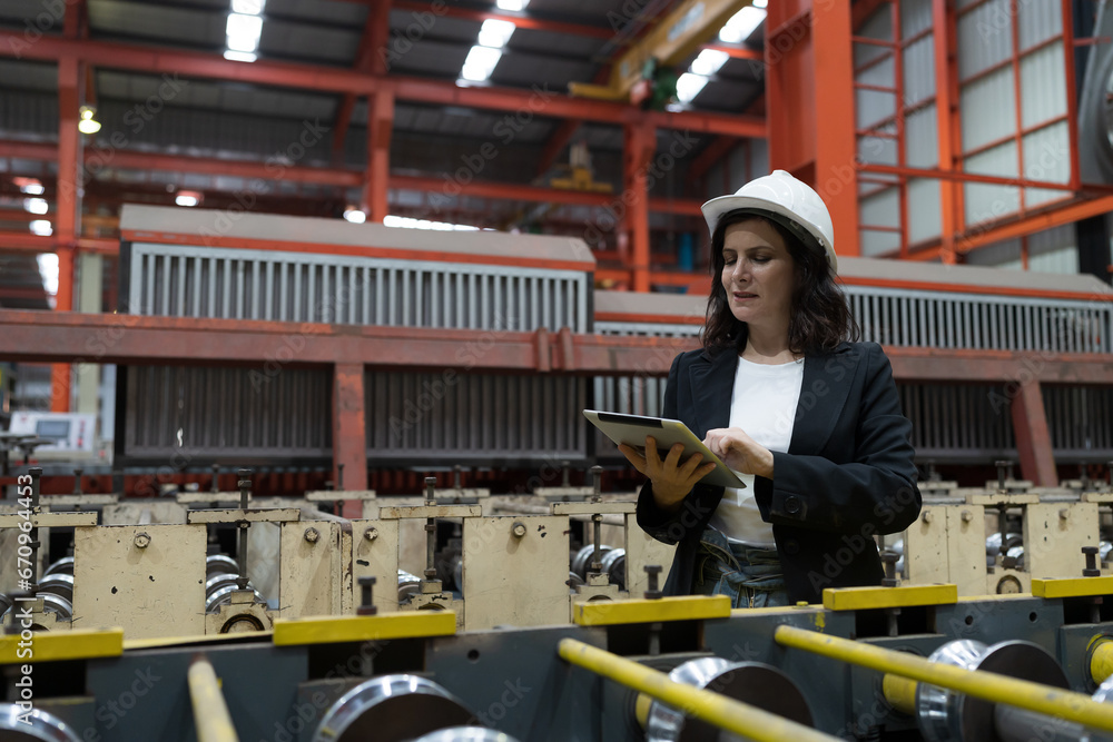 Female factory worker working and using digital tablet inspecting quality of production line conveyor in industry factory. Female inspector checking manufacturing process in plant Female factory worker working and using digital tablet inspecting quality of production line conveyor in industry factory. Female inspector checking manufacturing process in plant