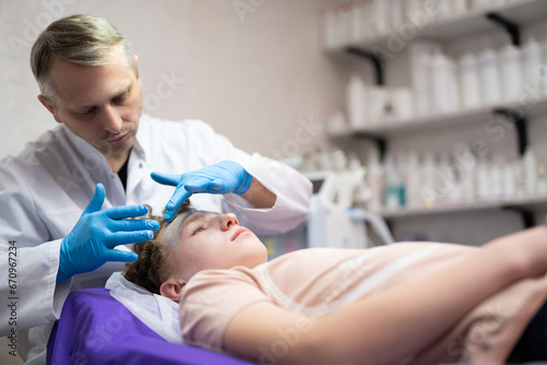 a cosmetologist doctor makes cosmetic procedures on the face of a young guy in a beauty salon