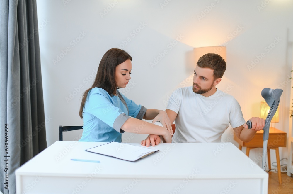 Obraz premium Beautiful young doctor putting a bandage on a male patient's arm after cleaning a wound in a hospital