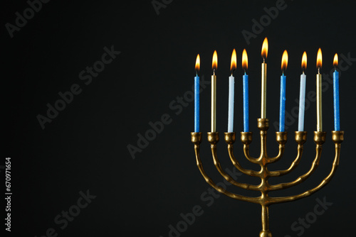 Hanukkiah with nine candles on black background, space for text