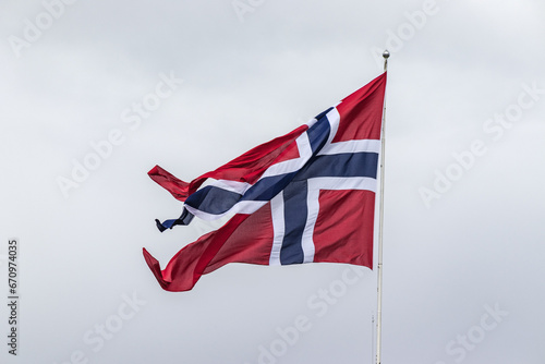 A flying Norwegian flag on a flagpole against the background of clouds. photo