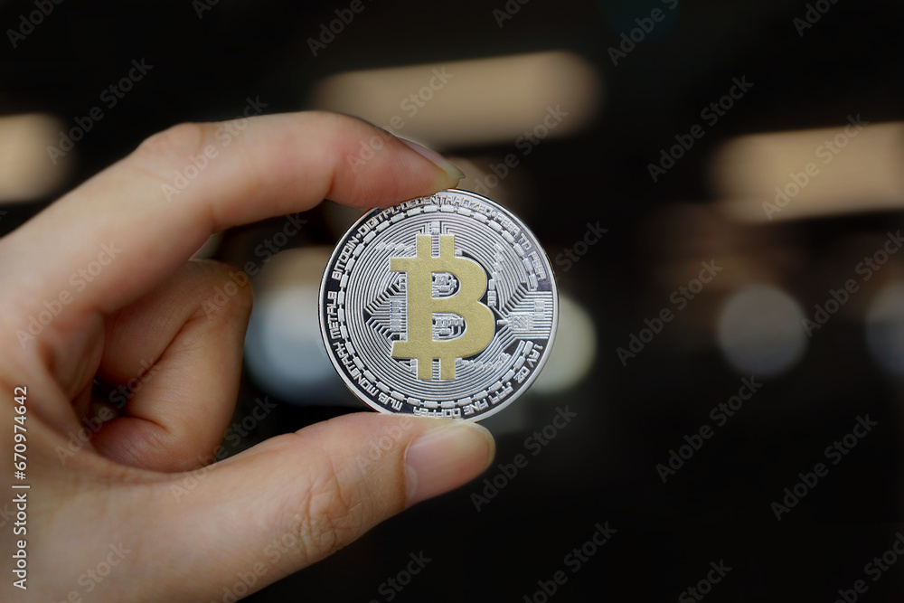 Cryptocurrency Silver golden bitcoin in hand on dark background with glowing bokeh lights Cryptocurrency Silver golden bitcoin in hand on dark background with glowing bokeh lights