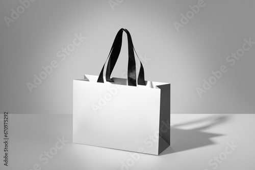 Mockup of a white paper bag without logo with black handles. White package on grey background