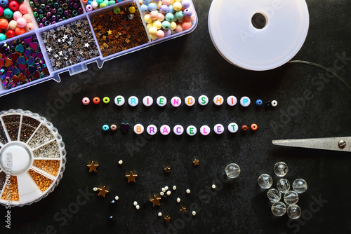 Obraz na płótnie Friendship bracelet letter beads and various other jewelry making supplies on dark background. Top view. w salonie