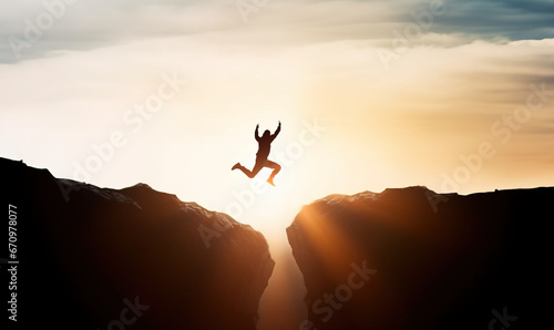 Man jumping over precipice between two rocky mountains at sunset. Freedom, risk, challenge, success photo