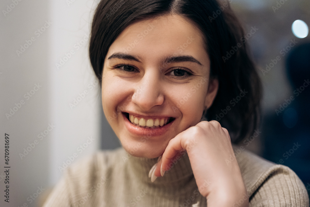 Young pretty woman sitting inside cafe waiting for order smiling, joyful

