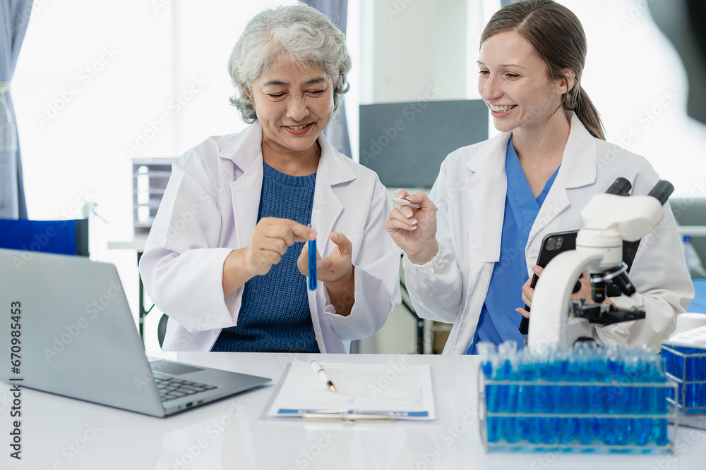 Fototapeta premium Beautiful young female scientist and two elderly women work in a laboratory with test tubes researching blue chemicals in the healthcare industry.