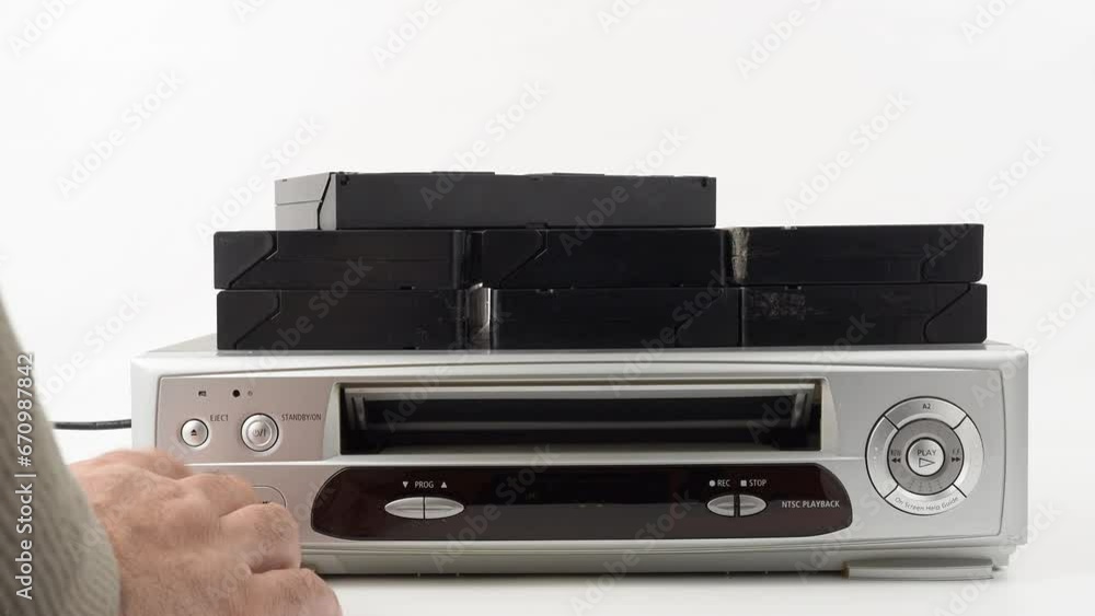 VHS video cassette recorder on a white background. Close-up of a man's hand pulling a video cassette out of a VCR. VHS video cassette recorder on a white background. Close-up of a man's hand pulling a video cassette out of a VCR.
