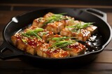 tofu steaks in a cast-iron skillet, sizzling in teriyaki sauce