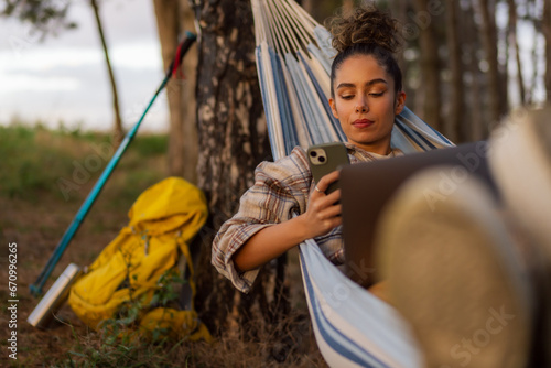 The hiker girl maximizes productivity from her hammock, effortlessly juggling tasks on her laptop and phone.