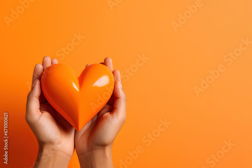 hand holds a heart love shape on an orange background with copy space photo