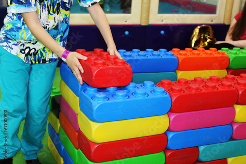 the child's hands build a wall of toy building blocks of different colors