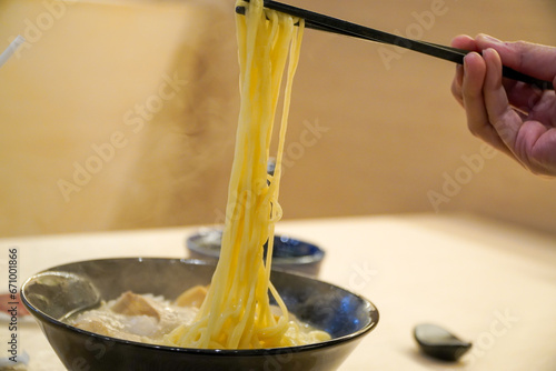 Cooking Japanese noodle soup in a restaurant,with steam and smoke in bowl on wooden background Focus on selecting Asian dishes on the table. Junk food concept