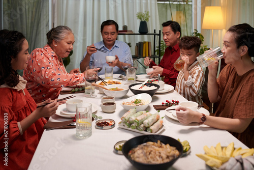 Big family enjoying dishes of Vietnamese cuisine at dinner party
