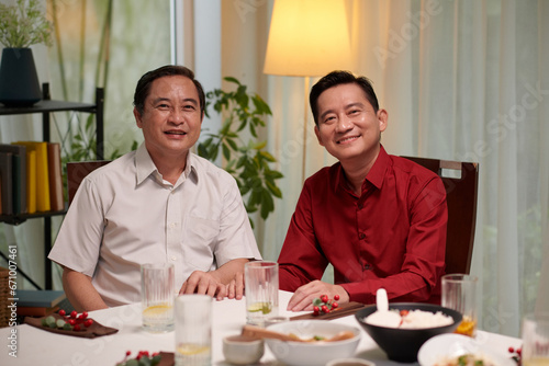 Cheerful mature Vietnamese men attending family dinner