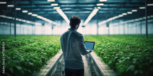Female supervisor, studying plant data on iPad in hydroponic hi-tech greenhouse, 