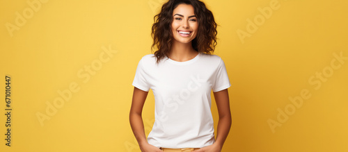 A young woman on a yellow studio background, smiling lightheartedly, wearing a white t-shirt photo