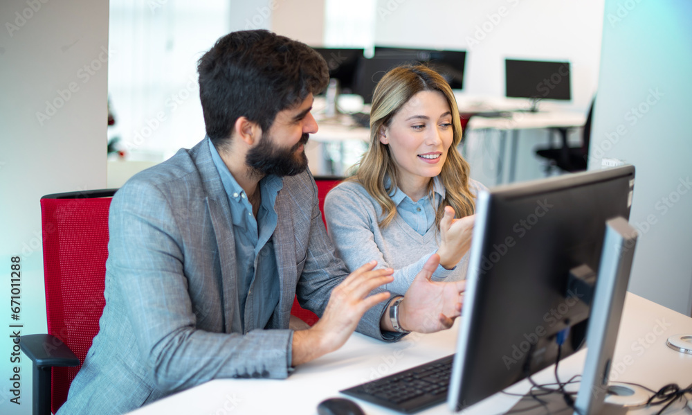 Two diverse businesspeople chatting sitting behind computer in office.Bearded businessman sharing ideas or startup business plan with female coworker. Two diverse businesspeople chatting sitting behind computer in office.Bearded businessman sharing ideas or startup business plan with female coworker.