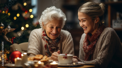 Happy grandmother drinking tea with granddaughter  Christmas tree at home