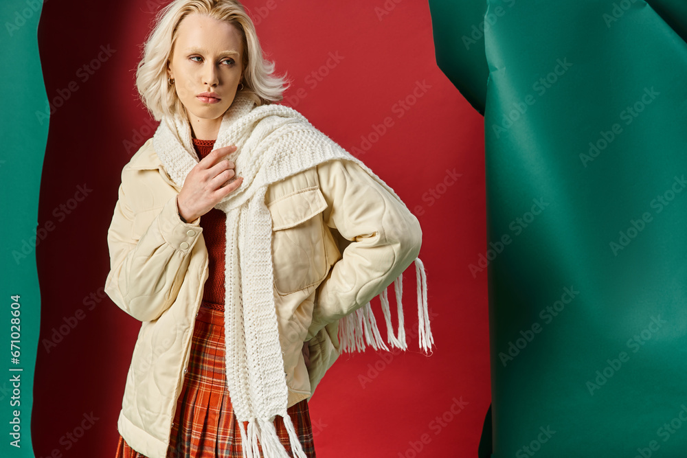 blonde woman in winter jacket, scarf and plaid skirt looking away on red with turquoise backdrop