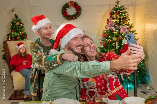 Family looking at camera selfie photo by smartphone in celebration party enjoy happy at dinner together with full food of turkey celebrate merry xmas in Christmas thanksgiving and New Year festive.
