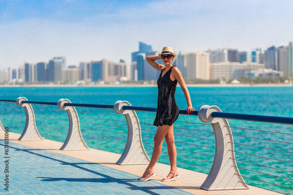 Tourist woman in Abu Dhabi, UAE. Sea and downtown with skyscrapers