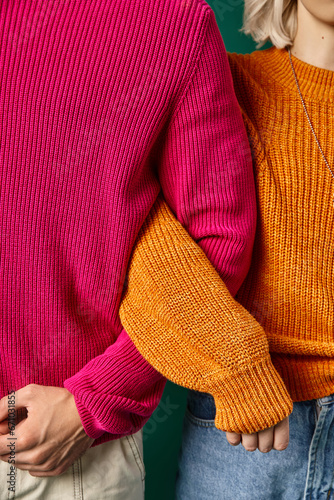 cropped view of young man and woman in knitted winter sweaters posing together, winter fashion