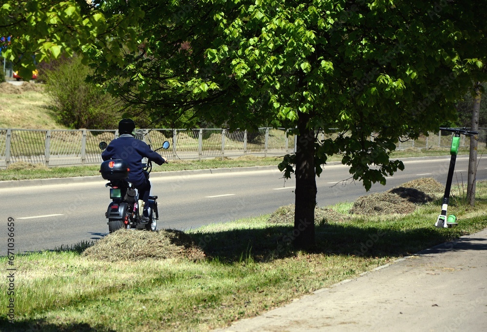 Obraz premium A man on an electric vehicle is driving down the road
