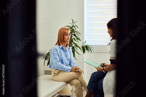 A patient and the doctor sitting in front of each other, in the doctor's office,  having a conversation.