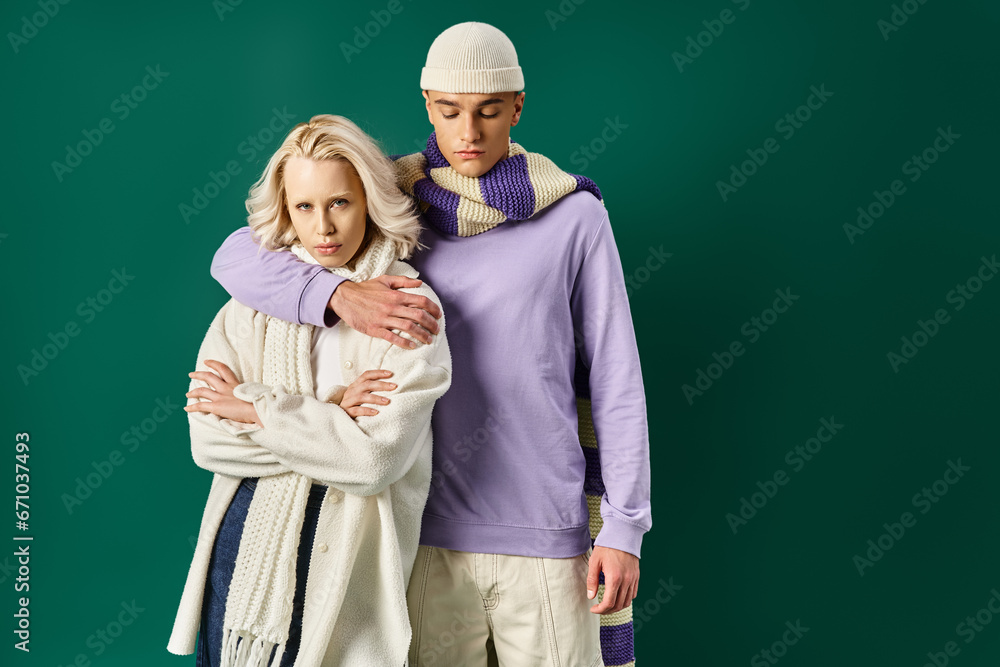 tall and stylish man hugging beautiful blonde woman in winter attire on turquoise backdrop tall and stylish man hugging beautiful blonde woman in winter attire on turquoise backdrop
