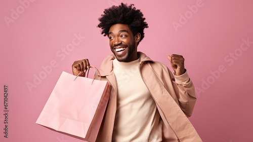 Young afro american woman smiling while holding shopping bags isolated on pink