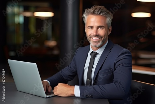 Smiling mid aged businessman ceo wearing suit sitting with laptop