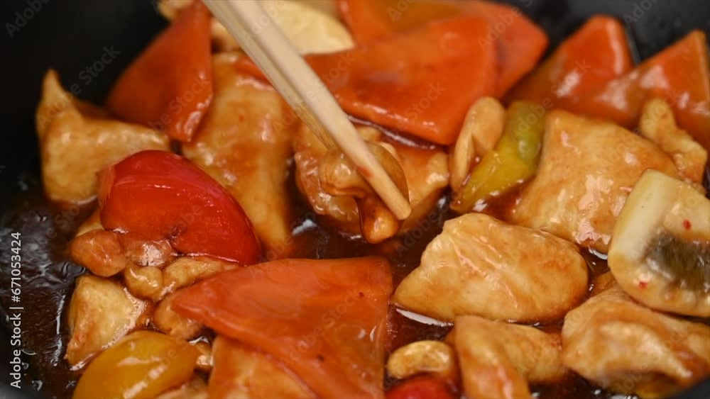 Woman eating chicken with vegetables and sweet sauce in a black pan at a chinese restaurant Woman eating chicken with vegetables and sweet sauce in a black pan at a chinese restaurant