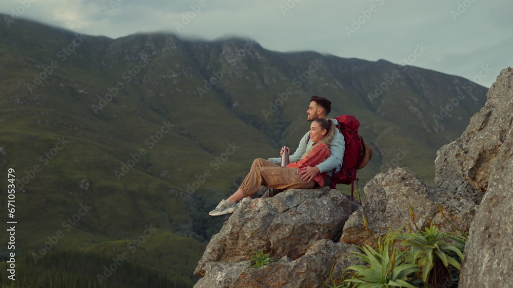 Hiking, mountains and view, couple relax on outdoor adventure and peace in nature with romance. Trekking, climbing and love, man and woman with view of natural landscape sitting on rocks together.
