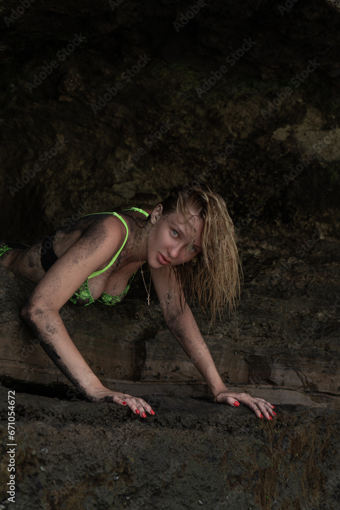 Sexy girl in green underwear posing against the background of rocks smeared with volcanic sand Sexy girl in green underwear posing against the background of rocks smeared with volcanic sand