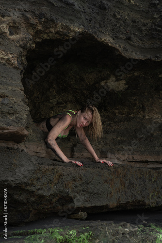 Sexy girl in green underwear posing against the background of rocks smeared with volcanic sand