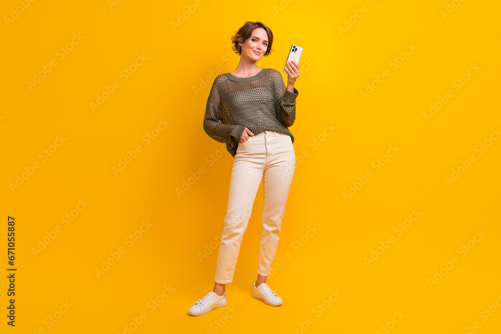 Fototapeta premium Full length photo of adorable cute girl dressed stylish clothes buy modern device iphone samsung isolated on yellow color background