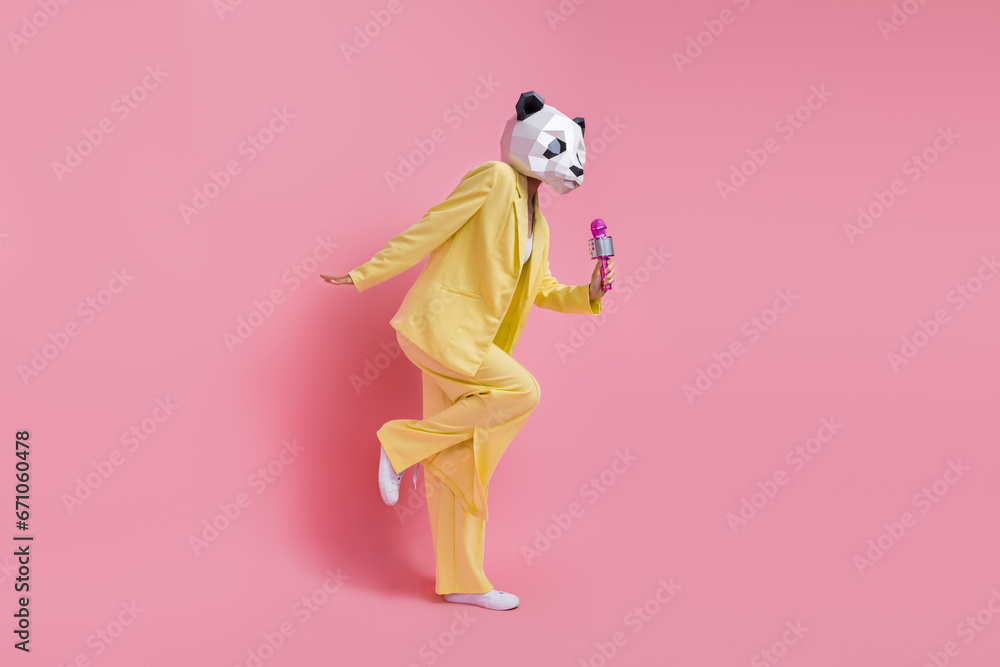 Full body profile portrait of charismatic weird 3d panda mask lady hold mic sing dance isolated on pink color background Full body profile portrait of charismatic weird 3d panda mask lady hold mic sing dance isolated on pink color background