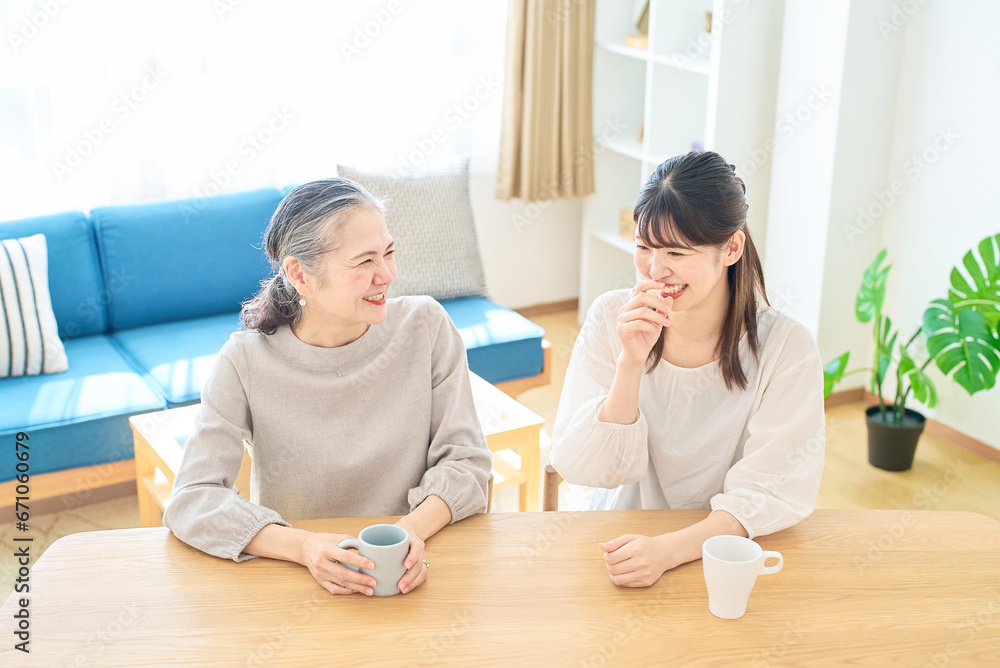 部屋で仲良く話すシニア女性と若い女性 部屋で仲良く話すシニア女性と若い女性
