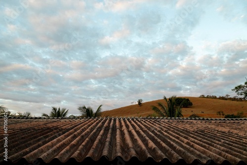 Telhado de telha de amianto ao fundo serra e céu azul.  photo