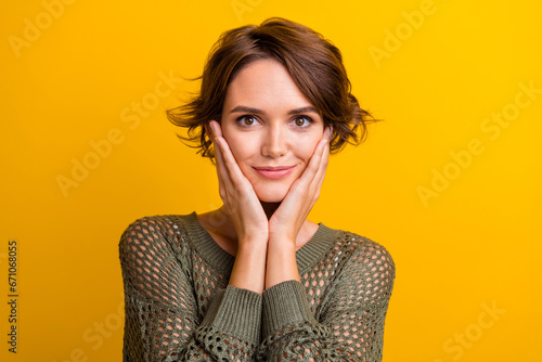 Photo portrait of lovely young lady touch cheeks adorable wear trendy knitwear khaki garment isolated on yellow color background