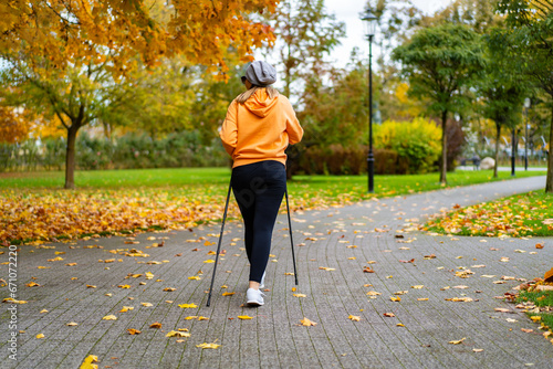 Nordic walking - mid-adult woman exercising in city park 